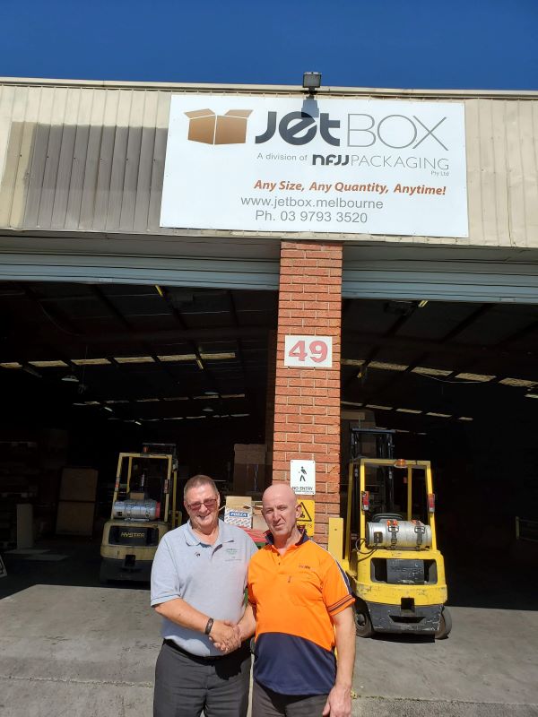 Box Latch - Two men, Phil Southam (left) Box Latch™ Products Australian Associate and Jet Lumani shaking hands outside a warehouse.