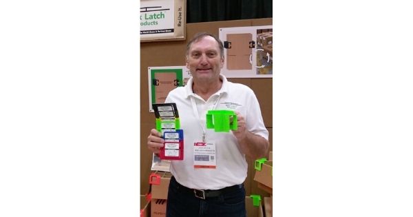Box Latch - Jack Wilson holding products while standing in a trade show booth.